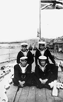 Crew members from Dragon pose for a photo at the bow of the ship during a harbour visit in the 1920s. StateLibQld 1 63927 Dragon (ship).jpg