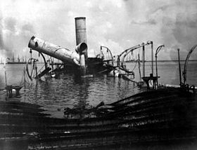 Sort og hvidt foto af resterne af et skib, der stikker ud fra vandoverfladen