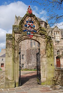 This archway, designed by AM Mackenzie, leading to the forecourt of the New King's Building at King's College portrays, from top to bottom, the coat of arms of Scotland, the coat of arms of Bishop Elphinstone, and the university's coat of arms. It is also engraved with the university's Latin motto, Initium Sapientiae Timor Domini. University of Aberdeen archway.jpg