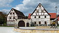 Bauernhof (Dreiseithof) mit Wohnstallhaus (Fachwerk), Seitengebäude (Fachwerk), Scheune und zwei Erdkellern, dazu Torbogen und Pforte