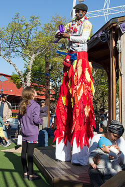 Stilt-walker modelling a balloon for a small girl