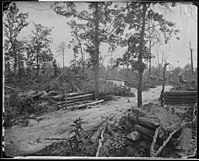 La fotografía en blanco y negro muestra una carretera y algunas fortificaciones de campo.