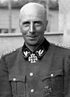 A hatless man wearing a military uniform with a neck order in the shape of a cross.