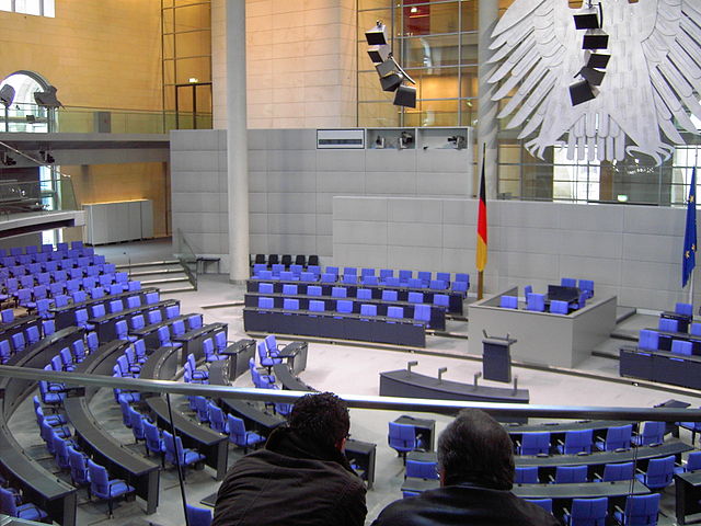 The cabinet bench in the Reichstag building (to the left of the flag) with the raised seat of the chancellor in the front row
