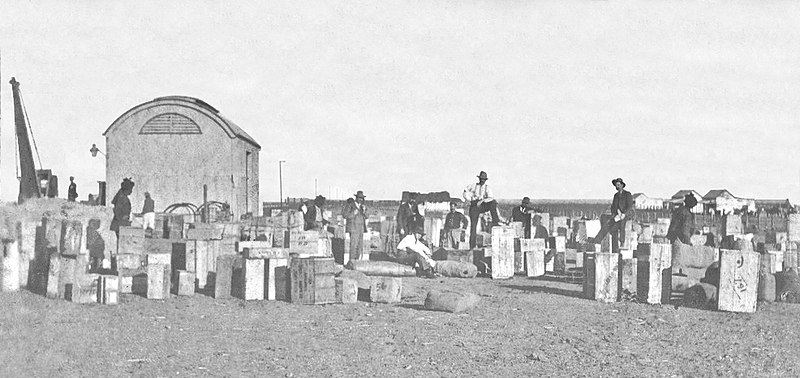 File:Goods being assembled at Oodnadatta railway station for northwards transport by camel, ca 1902 (SLSA B 64153-34).jpg