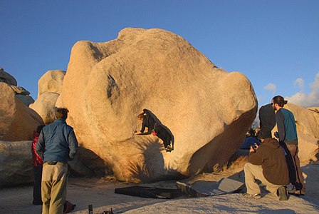 Climber on Stem Gem a classic V4 boulder problem in Joshua Tree National Park in Hidden Valley Campground