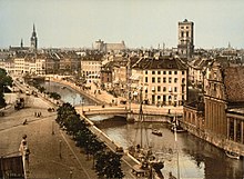 Slotsholmen canal, as seen from the Borsen building (c. 1900). In the background from left to right: Church of the Holy Ghost, Trinitatis Complex, St. Nicholas Church and Holmen Church. KBH 1890-1900.jpg