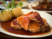 Krustenbraten mit Dunkelbiersoße, cerdo al horno servido con salsa de cerveza oscura.