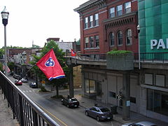 View of a street. There are many cars and people decorating the street.