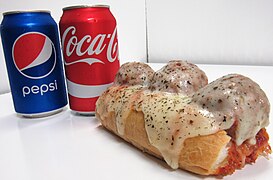 A meatball sub with melted mozzarella and parmesan, marinara sauce, and sprinkled with basil.