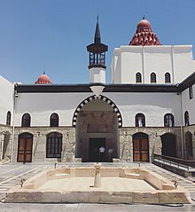 A courtyard in the center of a building with black accents and red domelike structures atop roofs.