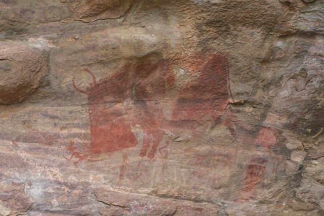 Mesolithic rock art at the Bhimbetka rock shelters, Madhya Pradesh, showing a wild animal, perhaps a mythical one, attacking human hunters. Although t