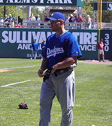 Baseballista gra w piłkę w bramce na Spring Training.  Ma na sobie niebieską koszulkę z napisem „Dodgers” z przodu.