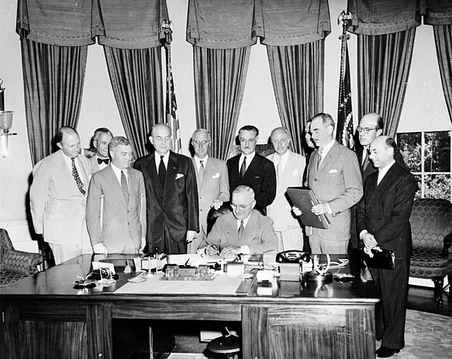 President Truman signing the North Atlantic Treaty with Portuguese Ambassador Teotónio Pereira standing behind