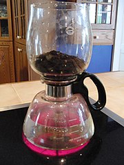 Step 3: The stem of the coffee ground container is inserted into the top of the glass carafe while the water continues to boil.