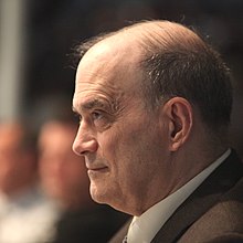 Perfil izquierdo de William Binney, mirando al frente con la ceja arqueada y una ligera sonrisa.