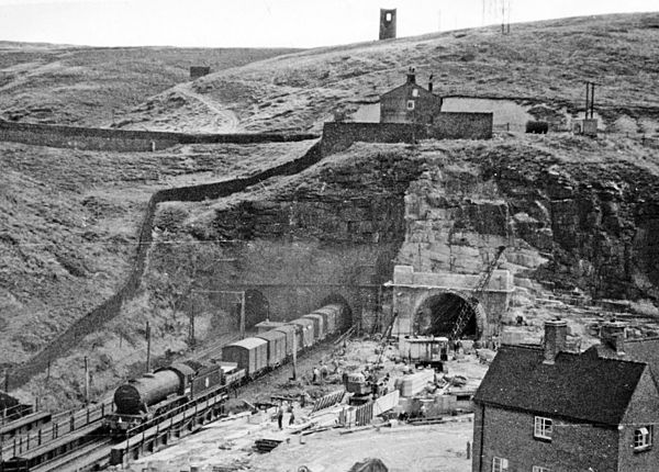 The western portals of the Woodhead tunnels in 1953. On the left, a train emerges from one of the original tunnels. Tunnel 3 is under construction on 