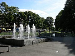 Foto eines Springbrunnens mit mehreren Fontänen in einem Park