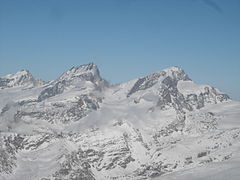 Le Rimpfischhorn, au centre entre l'Allalinhorn, et le Strahlhorn, avec à gauche du sommet, le Grand Gendarme et les cinq pointes de l'arête nord, et à droite l'antécime et l'épaule sud.