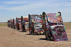 A row of buried Cadillacs painted in rainbow hues Cadillac Ranch in Texas (9313106739).jpg