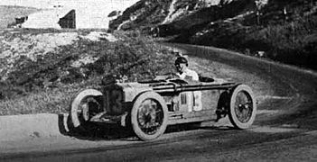 Foto van een raceauto die tegen de lage muur rechts ervan veegt.