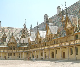 A large Burgundian building with cloister, balcony, and many ornate dormers