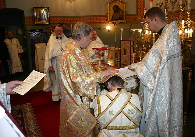 Eastern Orthodox subdeacon being ordained to the diaconate. The bishop has placed his omophorion and right hand on the candidate's head and is reading