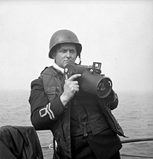 Lieutenant Gilbert A. Milne of the RCNVR, holding a Fairchild K-20 camera LtGilbertMilneRCNVR2June1944.jpg