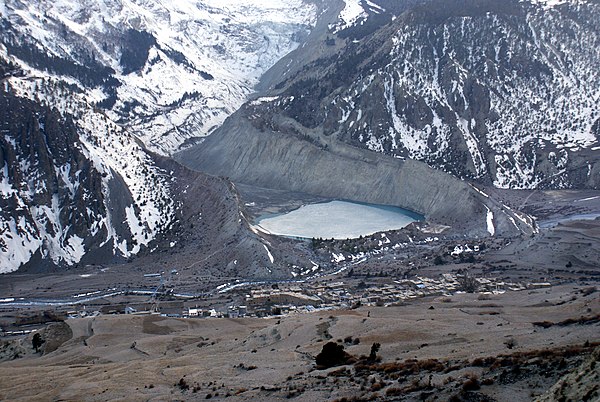 The snow-free debris hills around the lagoon are lateral and terminal moraines of a valley glacier in Manang, Nepal.