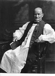 Black and white photograph of a man seated, wearing Church of England episcopal habit
