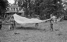 1st Airborne Division soldiers in front of the Hartenstein Hotel in Oosterbeek use yellow parachutes to signal to Allied supply aircraft on 23 September 1944 Operation 'market Garden' - the Battle For Arnhem, September 1944 BU1119.jpg