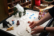 An individual engaging in sandplay therapy. Sandspiel1.jpg