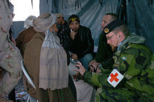 A Swedish Army medic wearing a Red Cross treats an Afghan civilian in 2006, during the War in Afghanistan. They would be considered non-combatants in the war. Swedish medic in Afghanistan 2006.jpg