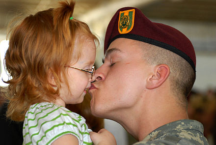 Ciuman kasih sayang seorang tentara dengan balita perempuan.