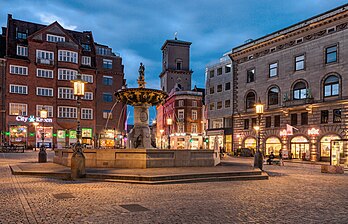 Caritasbrønden (Poço da Caridade) ao anoitecer, Copenhague, Dinamarca. É a fonte mais antiga de Copenhague, construída em 1608 na praça Gammeltorv em Strøget. A fonte foi construída por Cristiano IV sobre um dos poços da cidade e é considerada um dos melhores monumentos de Copenhague da Renascença. Na verdade, foi uma mudança e modernização de uma fonte mais antiga da época de Frederico II. A antiga fonte tinha um cano de água de madeira de 6 quilômetros de comprimento ligando o lago Emdrup a Gammeltorv, e como a diferença de nível entre o lago e a praça é de 9 metros, havia pressão de água suficiente para fazer uma fonte. Embora provavelmente fosse para decoração, o poço fazia parte do abastecimento normal de água da cidade. (definição 4 263 × 2 738)