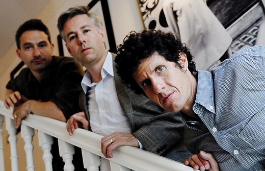 A group of three men on a stairwell behind a light background