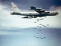 Mot en blå himmel med hvite skyer, slipper en B-52F bomber over Vietnam.