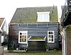 Houten huis met versierde makelaar op een der geveltoppen