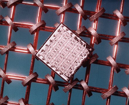 A 64 bit memory chip die, the SP95 Phase 2 Buffer Memory produced at IBM  mid 60s, versus memory core iron rings