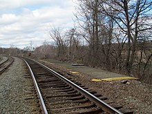 Uma plataforma ferroviária abandonada próxima a uma linha ferroviária ativa