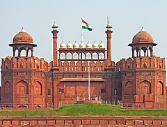 Bendera nasional India dikibarkan pada dinding yang dihiasi oleh kubah dan menara.