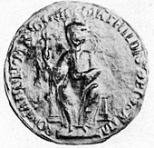 Photo d'un sceau abîmé montrant un personnage assis de face et levant la main droite