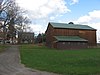 A brown wooden barn and a red brick farmhouse