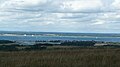 English: Yarmouth, Isle of Wight, seen from the top of Afton Down. To the left of the photo is Yarmouth Harbour. In the middle and to the right of the photo is Yarmouth town and the residential area. The large strip of sea across the middle is the Solent. Behind the Solent on the mainland is the New Forest. At the far left of that, is the town of Lymington. Three of Wightlink's ferries can be seen on the Lymington-Yarmouth service, one docked at Yarmouth, and the other two near Lymington.