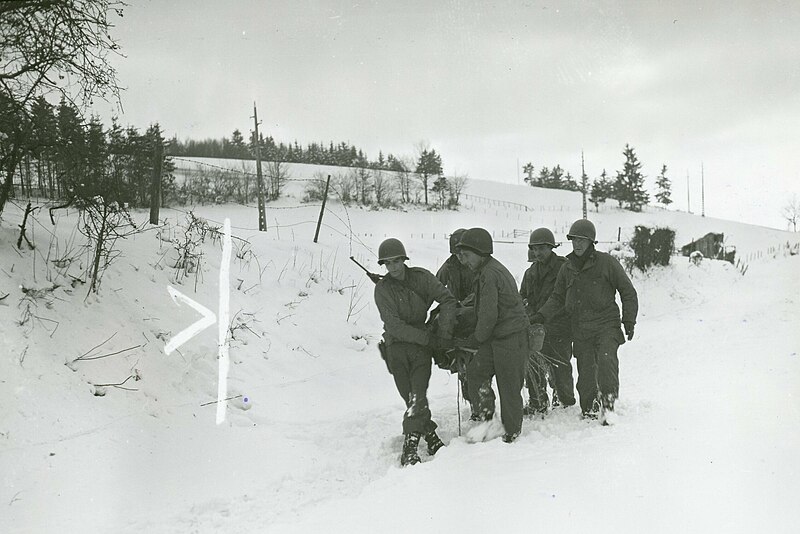 File:111-SC-199231 - A wounded soldier is carried back to the aid post by his comrades, on a stretcher improvised from a door on which straw has been placed (cropped).jpg