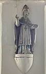 photo en couleurs de la statue de saint Thibaut sur un socle blanc fixé au mur.