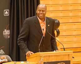 Craig Robinson, v kostýmu, na pódiu na tiskové konferenci.