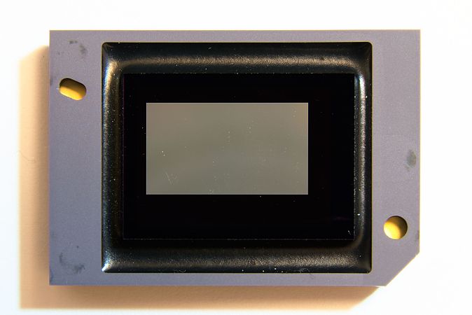 English: DMD chip from a videoprojector. View of the micromirrors. (About 3.2 × 2.2 cm (1.2 × 0.8 in)) Français : Puce DMD issue d'un vidéoprojecteur. Vue des micro-miroirs. (Environ 3.2 × 2.2 cm (1.2 × 0.8 in))