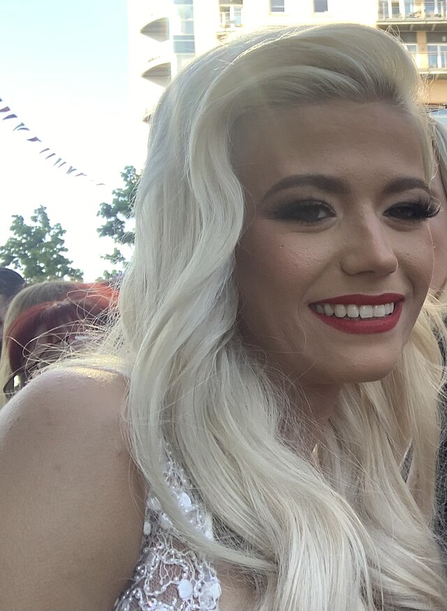Woman with platinum blonde hair smiling.