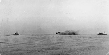 A distant view of Nigeria stopped and on fire after being torpedoed HMS Nigeria torpedoed.jpg